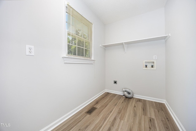 washroom with hookup for an electric dryer, washer hookup, light wood finished floors, and baseboards