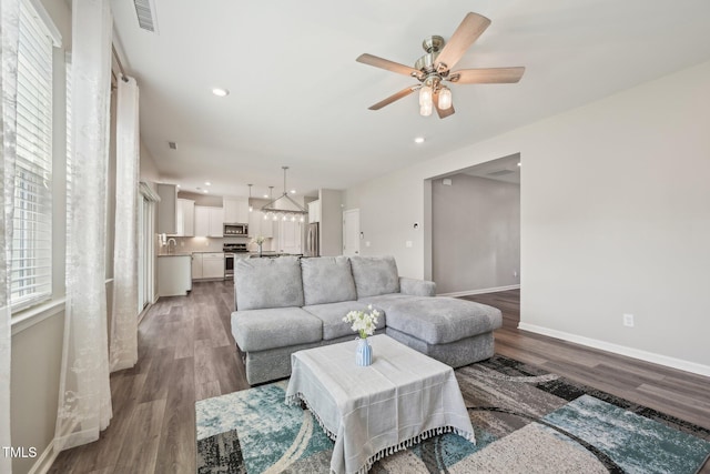 living room featuring wood finished floors, baseboards, ceiling fan, and recessed lighting