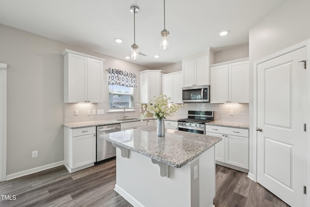 kitchen with stainless steel appliances, a sink, a kitchen island, decorative backsplash, and recessed lighting
