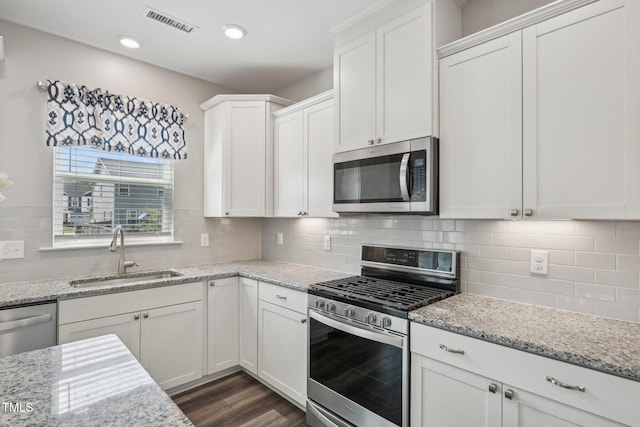 kitchen with stainless steel appliances, a sink, white cabinets, decorative backsplash, and recessed lighting