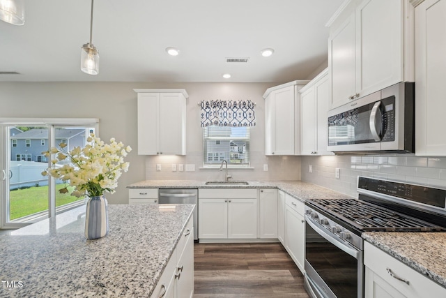 kitchen with stainless steel appliances, a sink, dark wood-style flooring, white cabinets, and decorative backsplash