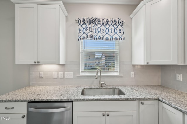kitchen with a sink, stainless steel dishwasher, backsplash, and white cabinets