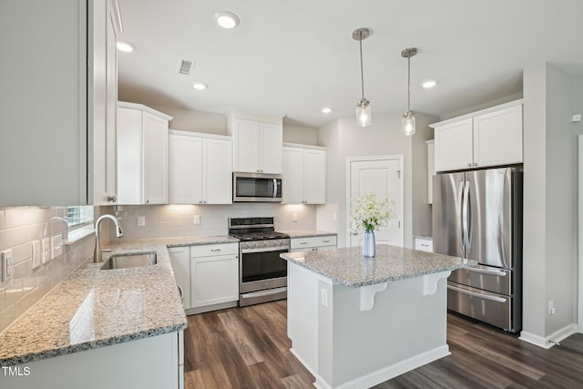 kitchen featuring stainless steel appliances, a sink, dark wood finished floors, a kitchen island, and recessed lighting