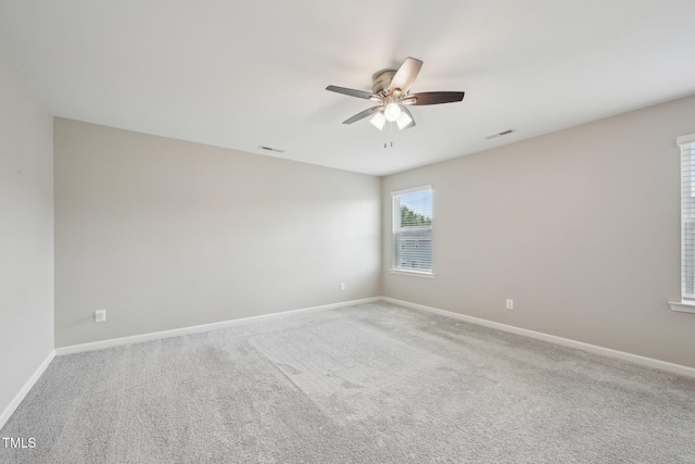 carpeted empty room with a ceiling fan and baseboards