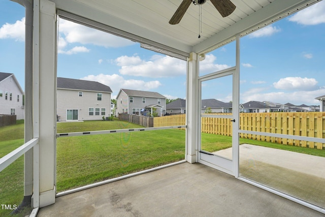 unfurnished sunroom with a residential view and ceiling fan