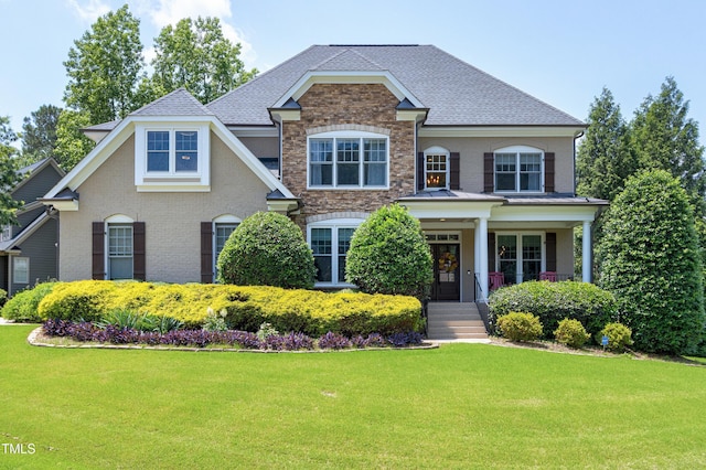 view of front of property featuring a front lawn, a shingled roof, brick siding, and stone siding
