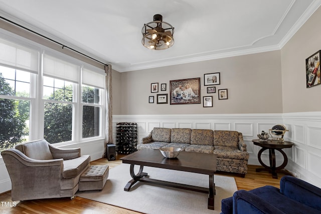 living room with crown molding, wood finished floors, and wainscoting