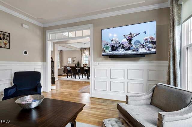 living room featuring ornamental molding, a wainscoted wall, and light wood-style flooring