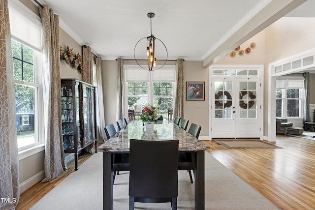 dining space with ornamental molding, plenty of natural light, light wood finished floors, french doors, and baseboards