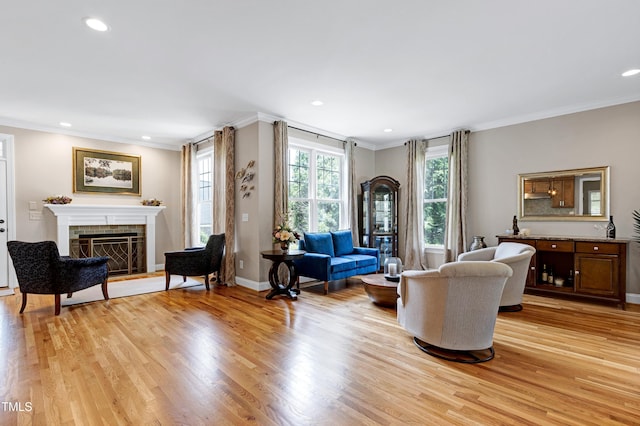 living area featuring crown molding, a fireplace, light wood finished floors, recessed lighting, and baseboards