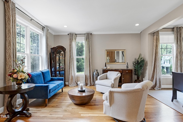 living area featuring healthy amount of natural light, light wood-type flooring, recessed lighting, ornamental molding, and baseboards