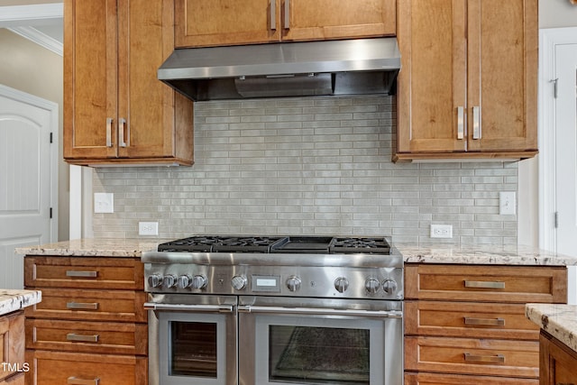 kitchen with under cabinet range hood, double oven range, ornamental molding, tasteful backsplash, and light stone counters