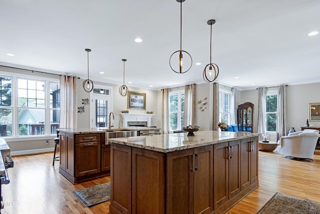 kitchen featuring open floor plan, a kitchen island, recessed lighting, light wood-style floors, and a fireplace