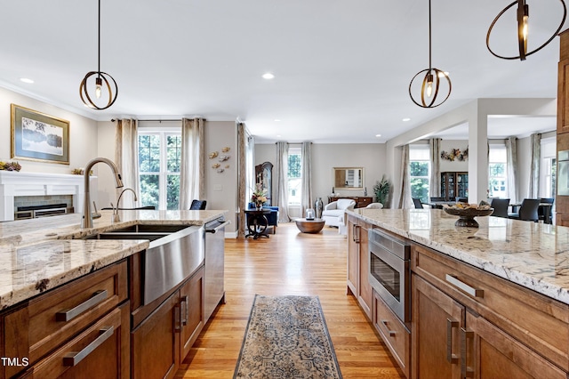 kitchen with brown cabinets, stainless steel appliances, open floor plan, a sink, and plenty of natural light