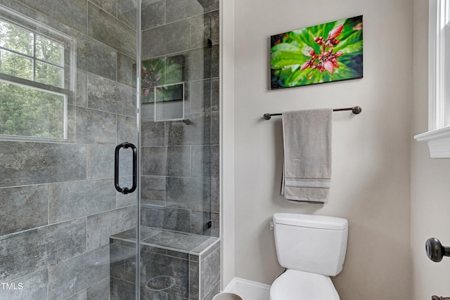 bathroom with a stall shower, toilet, and baseboards