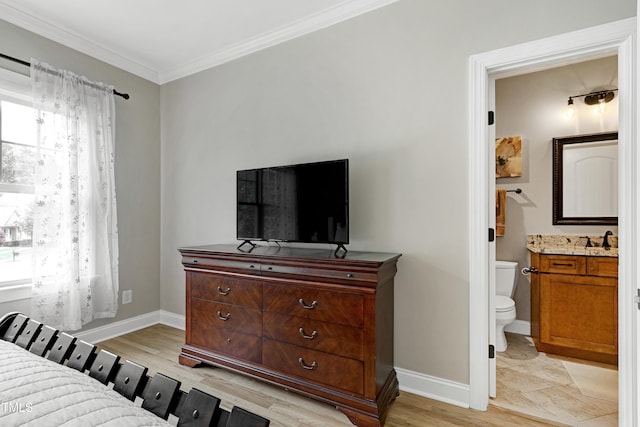 bedroom with baseboards, ornamental molding, a sink, light wood-style floors, and ensuite bath
