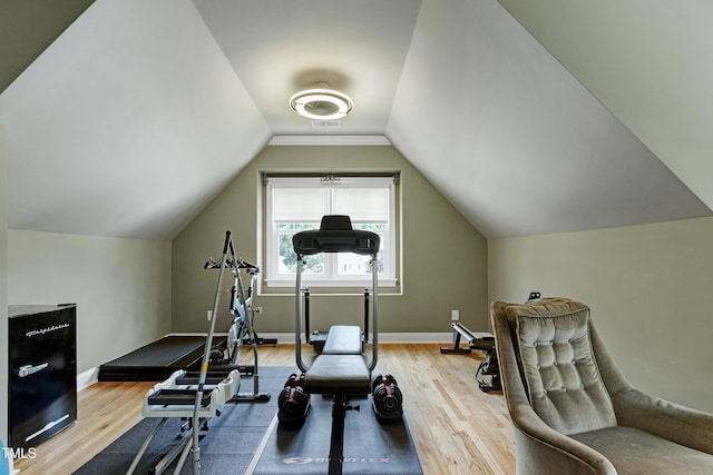 exercise room featuring wood finished floors, baseboards, and vaulted ceiling