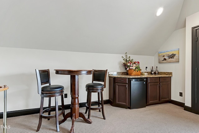 indoor dry bar featuring light colored carpet, vaulted ceiling, and baseboards