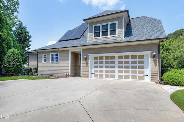 view of front of house with concrete driveway, roof mounted solar panels, a garage, and roof with shingles