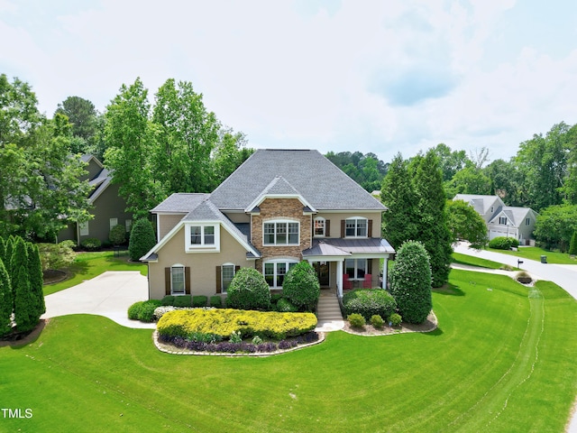 craftsman inspired home featuring stone siding, covered porch, a front yard, roof with shingles, and stucco siding