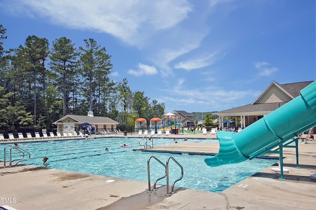 community pool featuring fence and a water slide