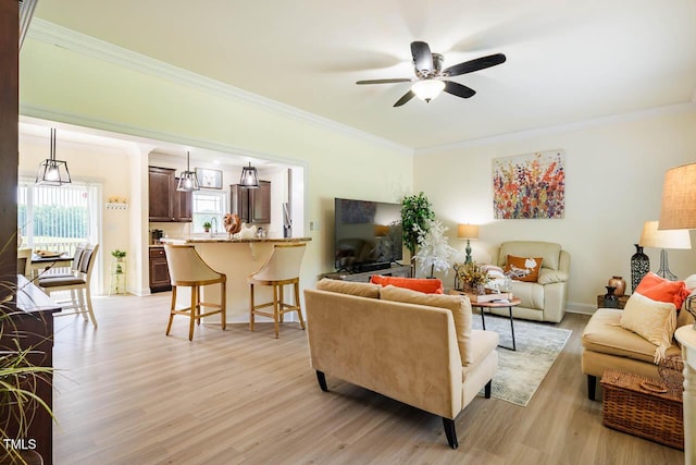 living room with ornamental molding, light wood finished floors, and ceiling fan