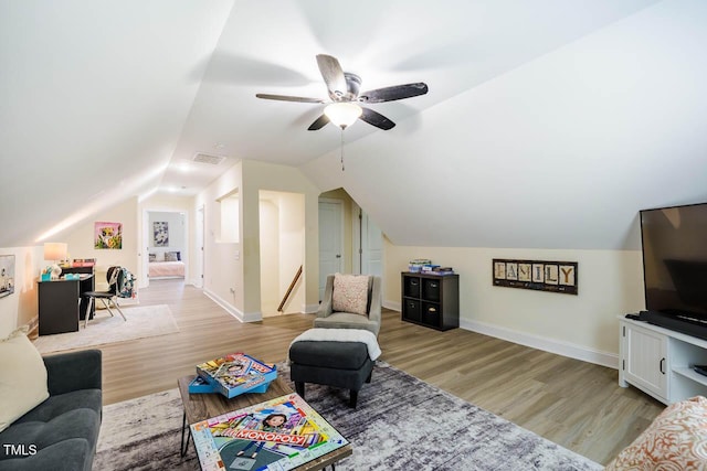 living area featuring wood finished floors, lofted ceiling, a ceiling fan, and baseboards