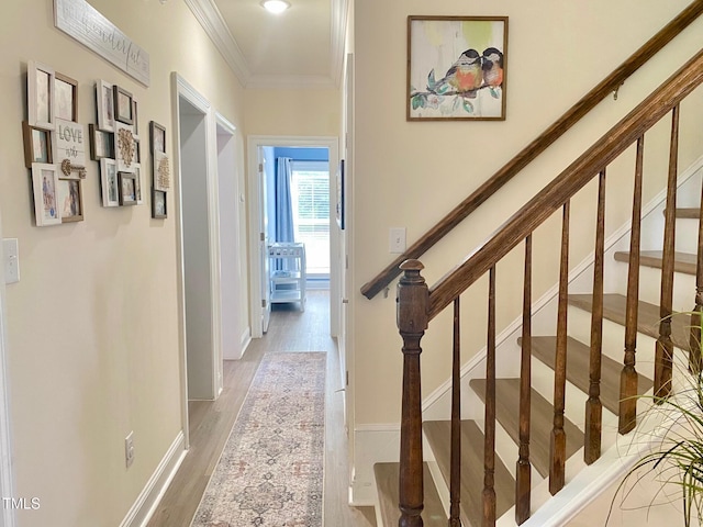 hallway featuring crown molding, wood finished floors, baseboards, and stairs