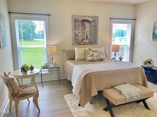 bedroom featuring multiple windows, light wood-type flooring, and baseboards