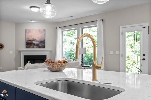 111 Chapel Run Way, Chapel Hill, NC 27517 - kitchen featuring a sink, blue cabinets, light stone countertops, open floor plan, and a glass covered fireplace