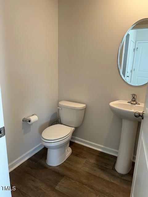bathroom featuring wood finished floors, baseboards, and toilet