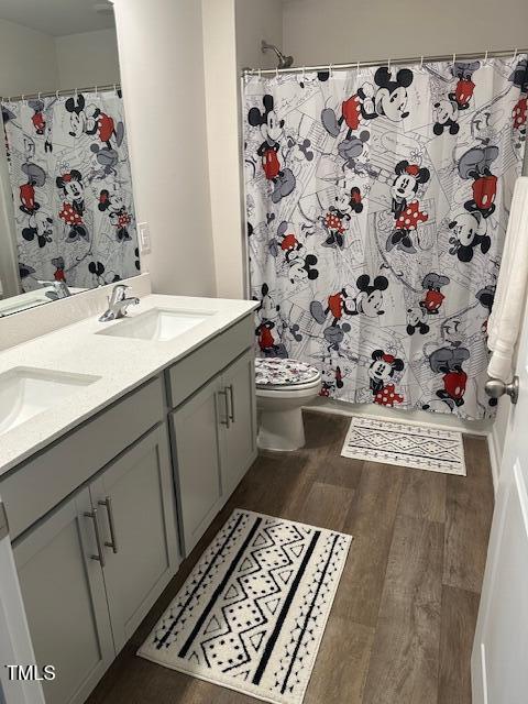 full bathroom with wood finished floors, double vanity, toilet, and a shower with shower curtain