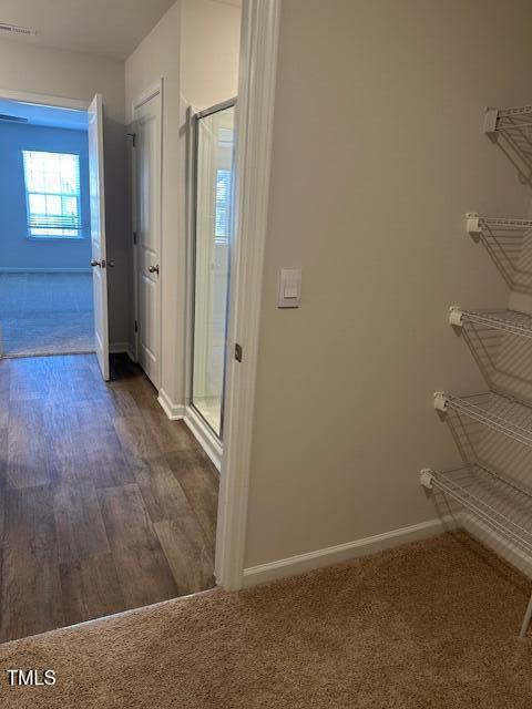 hallway featuring baseboards, dark colored carpet, and dark wood-style floors