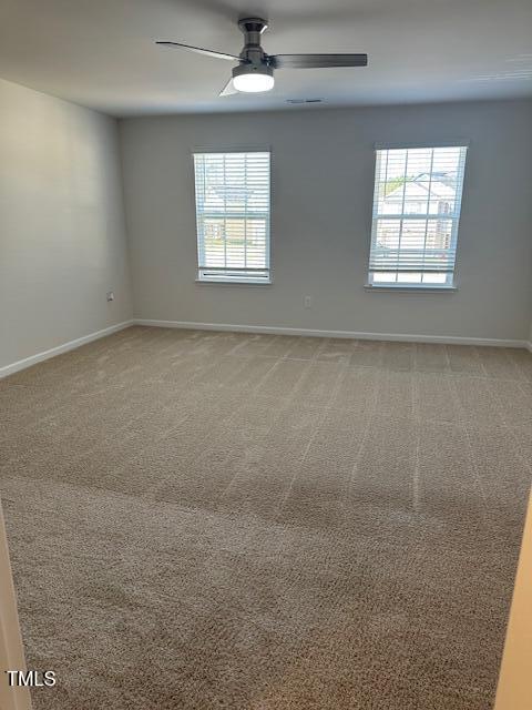 empty room with a ceiling fan, light colored carpet, and baseboards