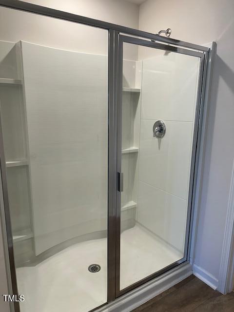 full bath featuring a stall shower and wood finished floors