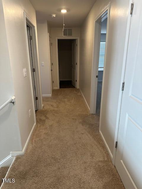 hallway featuring light carpet and baseboards