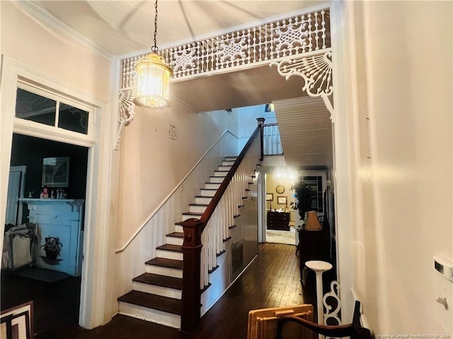 stairway featuring hardwood / wood-style flooring, a chandelier, and crown molding