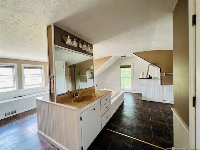 full bathroom featuring a textured ceiling, lofted ceiling, and vanity