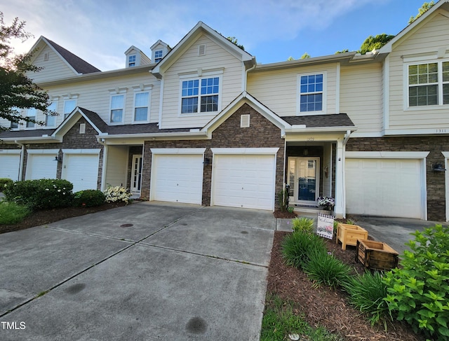 multi unit property with a garage, concrete driveway, and stone siding