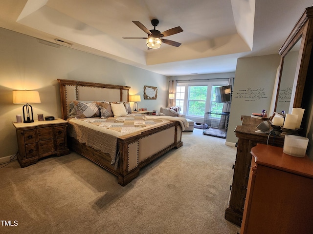 bedroom with a tray ceiling, light carpet, a ceiling fan, and baseboards