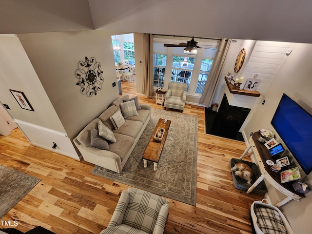 living area with wood finished floors, ceiling fan, and a fireplace