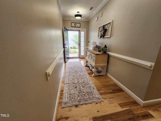 doorway to outside featuring light wood finished floors, ornamental molding, and baseboards