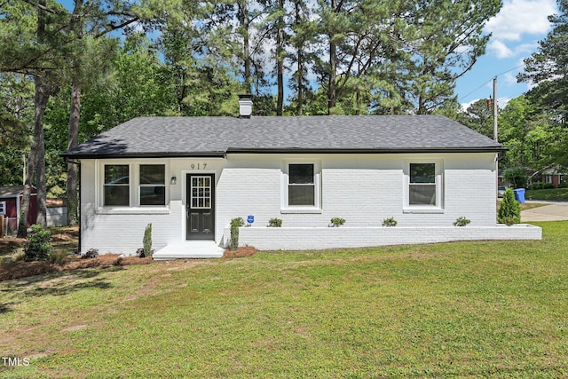 ranch-style home with brick siding, a front lawn, a chimney, and roof with shingles