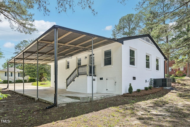 view of property exterior featuring central AC unit, brick siding, and a carport