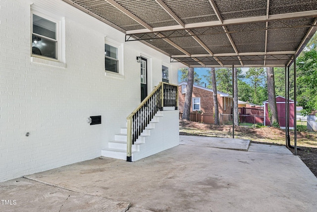 view of patio / terrace featuring fence, a storage unit, and an outbuilding