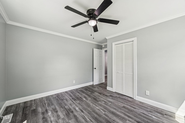 unfurnished bedroom featuring crown molding, dark wood-style flooring, baseboards, a closet, and a ceiling fan
