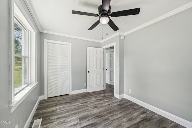 unfurnished bedroom featuring multiple windows, baseboards, dark wood finished floors, and ornamental molding