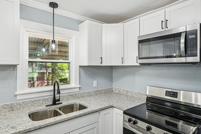 kitchen featuring appliances with stainless steel finishes, a sink, white cabinets, pendant lighting, and crown molding