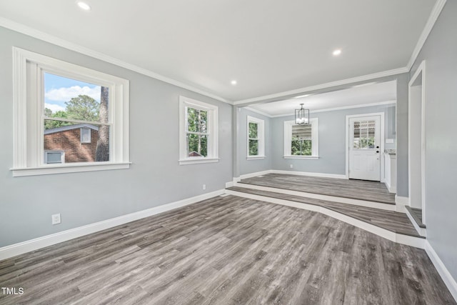 unfurnished living room with baseboards, wood finished floors, a chandelier, ornamental molding, and recessed lighting