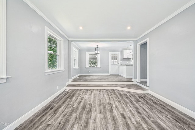 unfurnished living room featuring ornamental molding, wood finished floors, baseboards, recessed lighting, and a chandelier